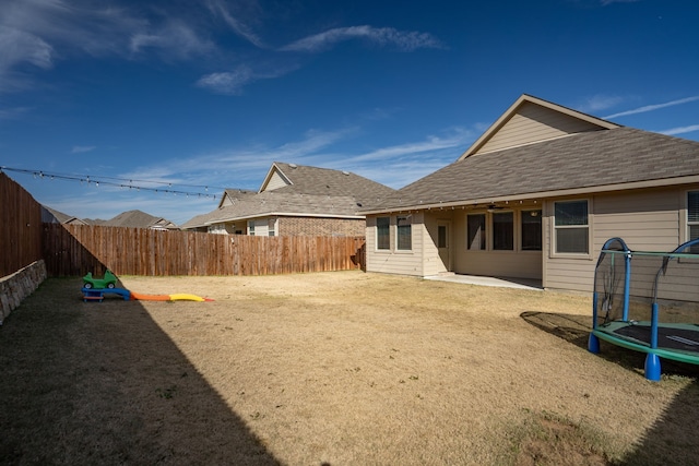 view of yard with a trampoline, a fenced backyard, and a patio