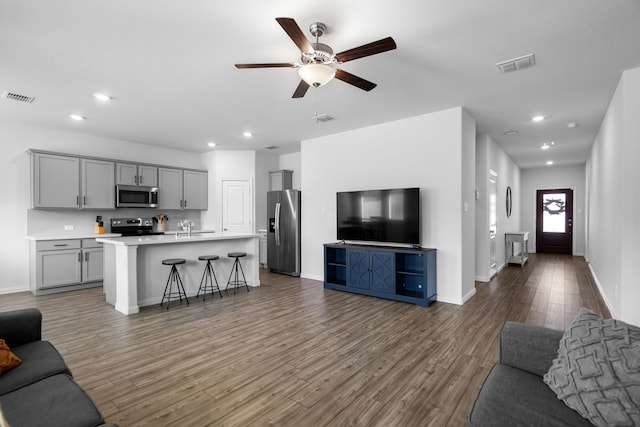 living room with recessed lighting, visible vents, and wood finished floors