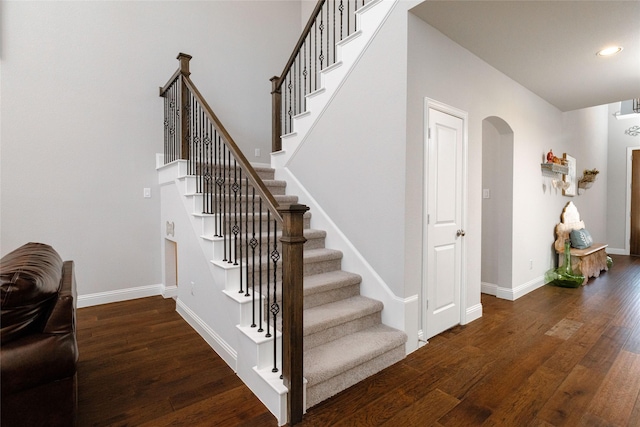 staircase featuring arched walkways, recessed lighting, baseboards, and wood finished floors