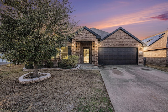 view of front of house with brick siding, an attached garage, and driveway