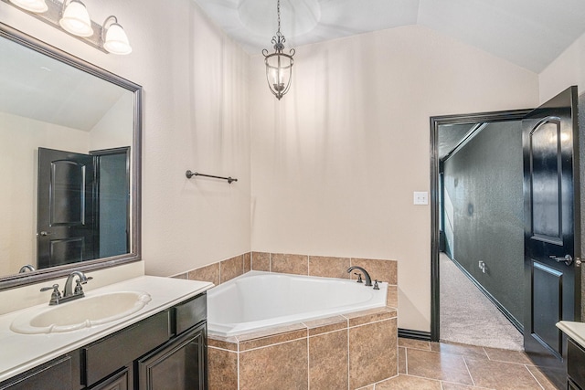 bathroom with vanity, vaulted ceiling, and a garden tub