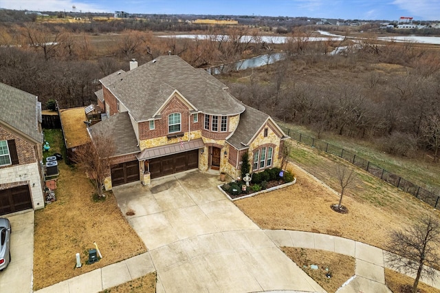 view of front of house featuring driveway, a garage, a shingled roof, a chimney, and brick siding