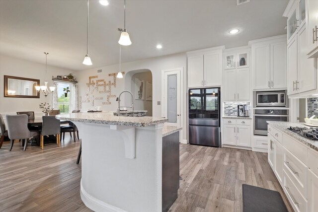 4109 Chantilly Ln, Frisco, TX 75036 - kitchen with stainless steel microwave, a sink, light wood finished floors, light stone countertops, and glass insert cabinets