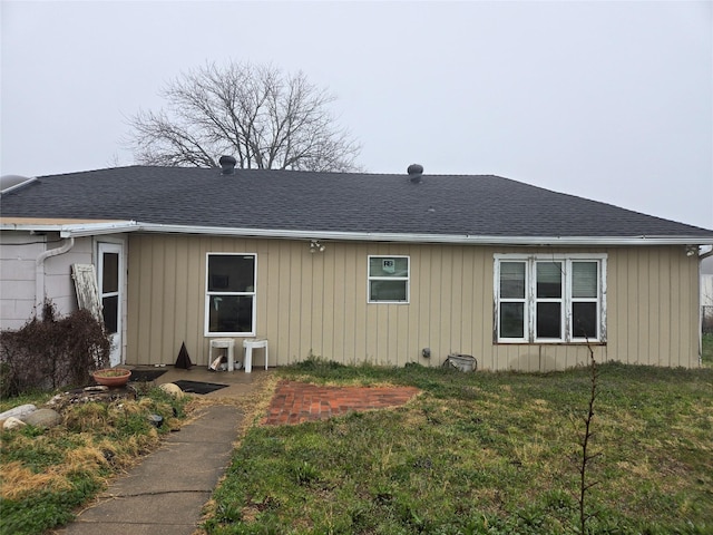 rear view of property with a lawn and roof with shingles