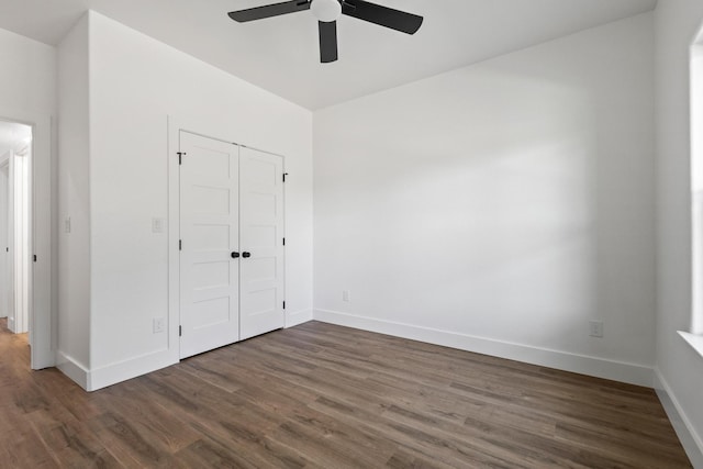 unfurnished bedroom with a ceiling fan, baseboards, a closet, and dark wood-style floors