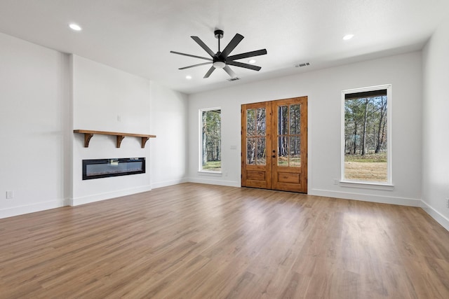 unfurnished living room with recessed lighting, wood finished floors, visible vents, baseboards, and a glass covered fireplace