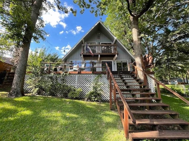 back of property featuring a balcony, a lawn, and stairway