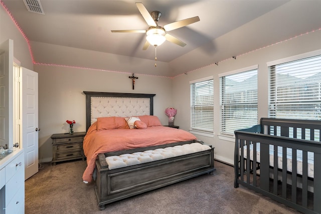 bedroom featuring vaulted ceiling, dark carpet, ceiling fan, and visible vents