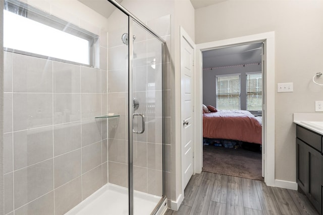 ensuite bathroom with ensuite bathroom, vanity, wood finished floors, and a stall shower