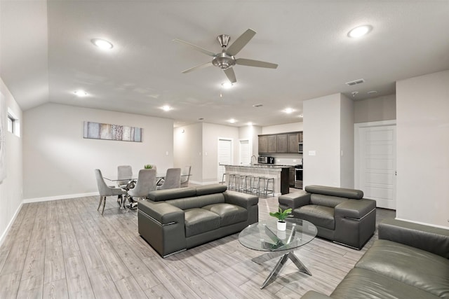 living area with ceiling fan, light wood finished floors, baseboards, visible vents, and lofted ceiling