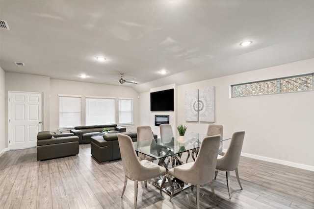 dining room featuring baseboards, visible vents, a fireplace, and light wood-type flooring