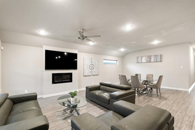 living room with baseboards, ceiling fan, light wood finished floors, and a glass covered fireplace