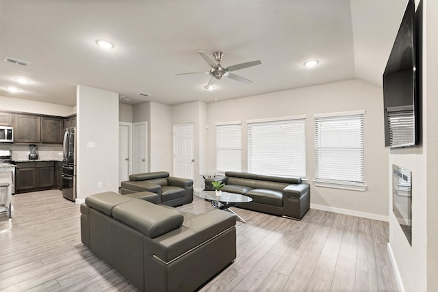 living area with light wood-type flooring, visible vents, ceiling fan, and baseboards