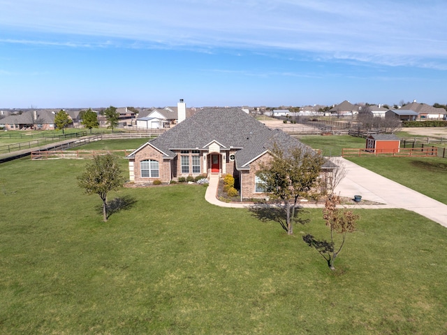 view of front of home with fence, a front yard, a residential view, brick siding, and a chimney