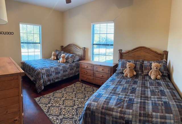 bedroom with ceiling fan, dark wood-style flooring, and multiple windows