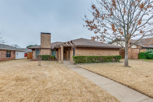 ranch-style house with brick siding, a chimney, and a front lawn