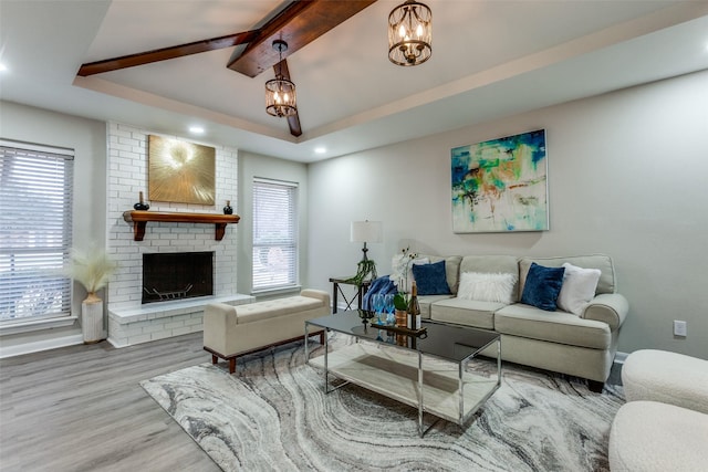 living area featuring wood finished floors, baseboards, a chandelier, a fireplace, and vaulted ceiling