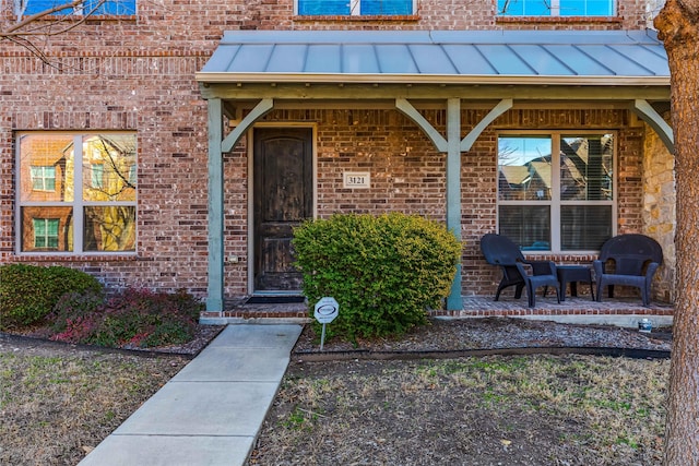 entrance to property featuring a standing seam roof, metal roof, and brick siding