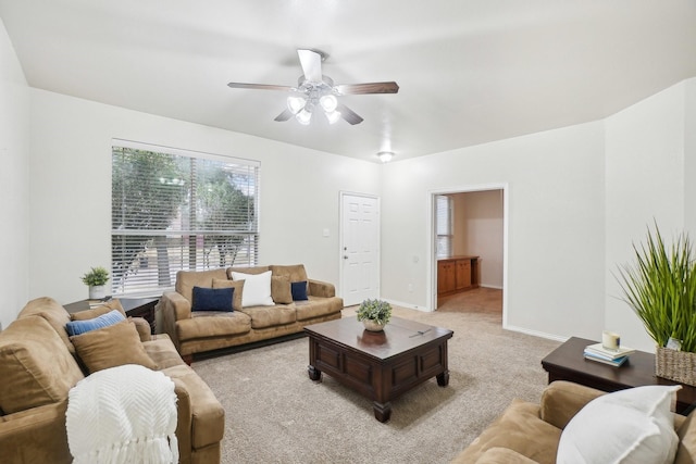 living room featuring baseboards, ceiling fan, and light carpet