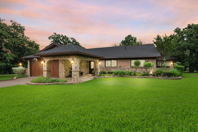 view of front of property featuring a garage, stone siding, a front lawn, and concrete driveway