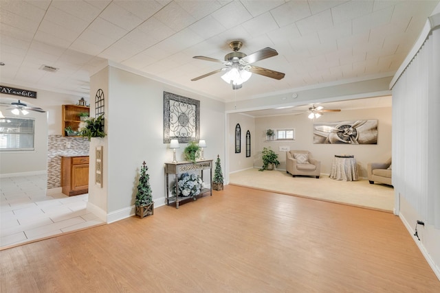 unfurnished room featuring baseboards, visible vents, a ceiling fan, crown molding, and light wood-type flooring