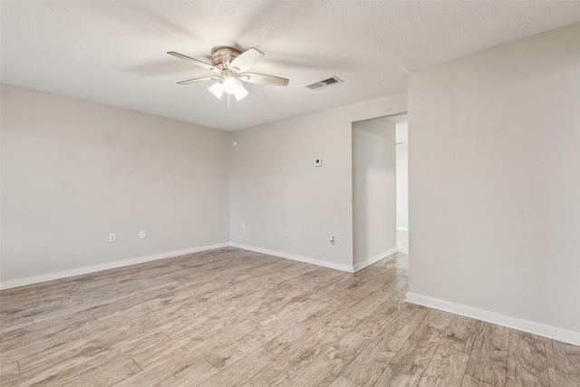 unfurnished room featuring ceiling fan, visible vents, baseboards, a textured ceiling, and light wood-type flooring