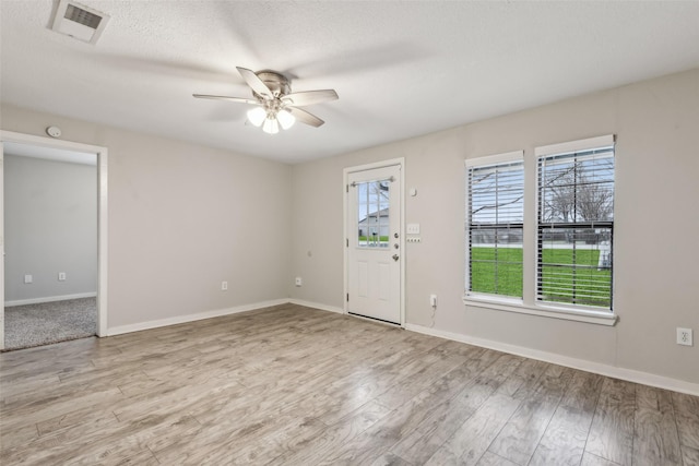 foyer featuring a ceiling fan, visible vents, baseboards, and light wood-type flooring