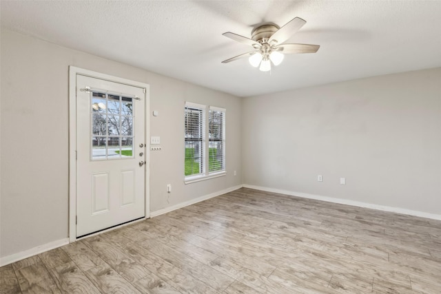 foyer featuring light wood-style flooring, baseboards, a ceiling fan, and a textured ceiling