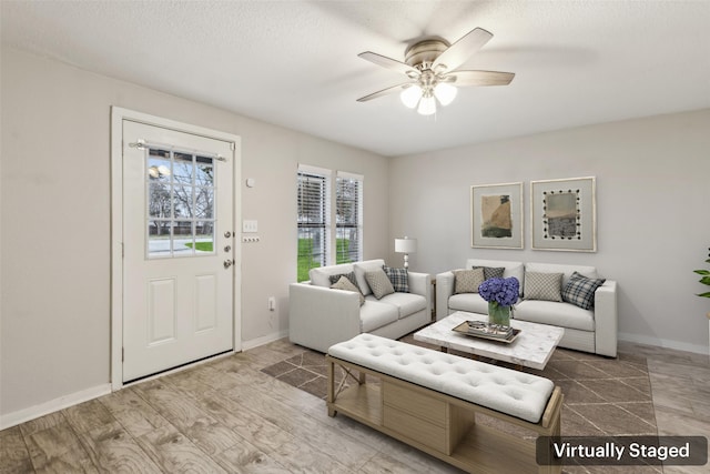 living room featuring a ceiling fan, baseboards, wood finished floors, and a textured ceiling