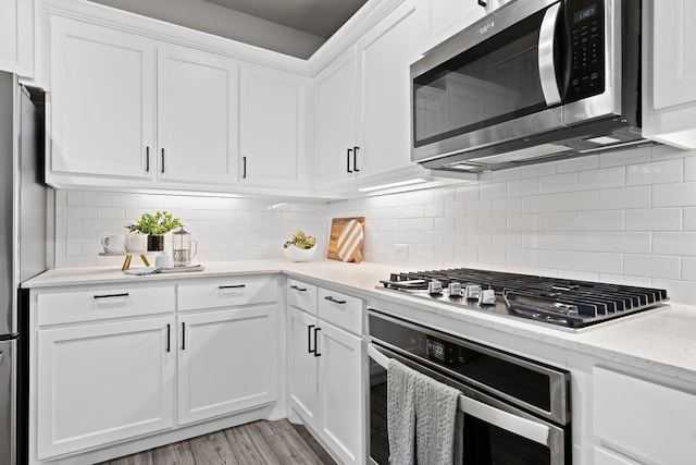 3002 Northshore Dr, Celina, TX 75009 - kitchen with appliances with stainless steel finishes, light wood-type flooring, white cabinetry, decorative backsplash, and light stone counters