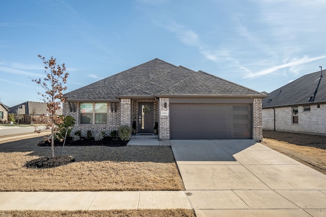 view of front facade with brick siding, a shingled roof, driveway, and a garage