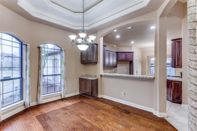 interior space with light stone counters, a tray ceiling, arched walkways, crown molding, and dark wood-type flooring