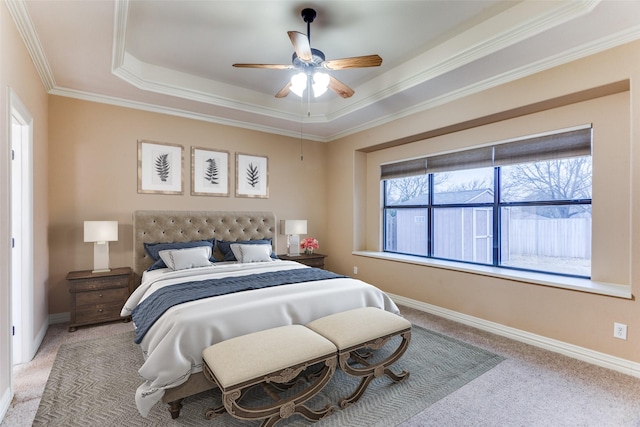 carpeted bedroom with a ceiling fan, baseboards, a raised ceiling, and crown molding