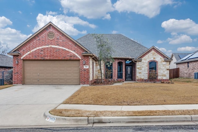 view of front of house with an attached garage, brick siding, concrete driveway, stone siding, and roof with shingles