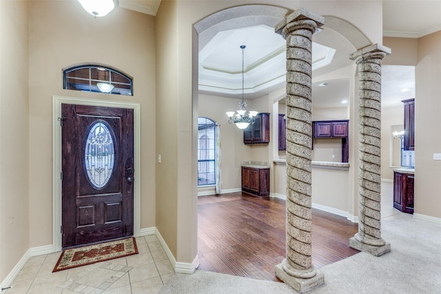 foyer featuring tile patterned flooring, baseboards, crown molding, and ornate columns