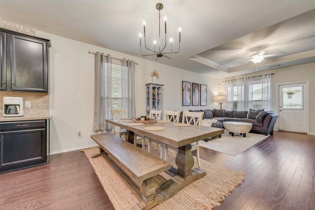 124 Feverbush Dr, Fate, TX 75189 - dining room with dark wood-style flooring, a chandelier, baseboards, a tray ceiling, and a ceiling fan