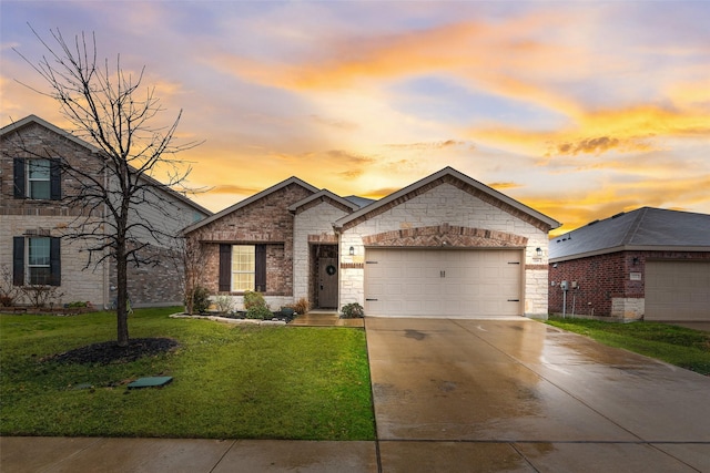 french country inspired facade with an attached garage, concrete driveway, and a front yard