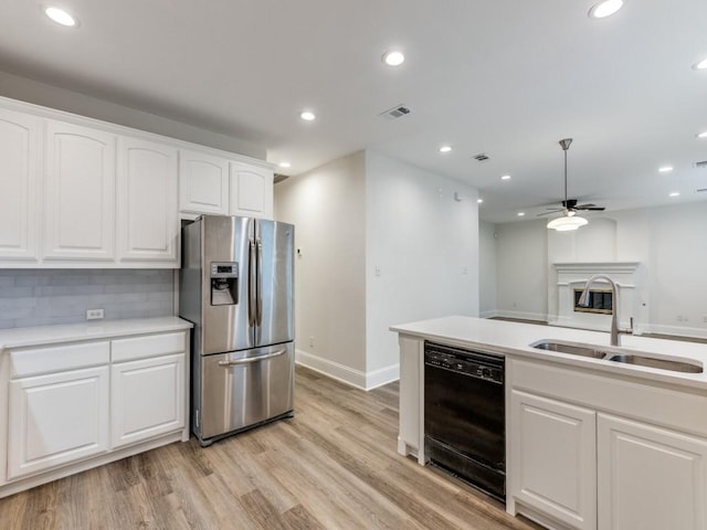 kitchen with dishwasher, a sink, stainless steel fridge, and white cabinetry