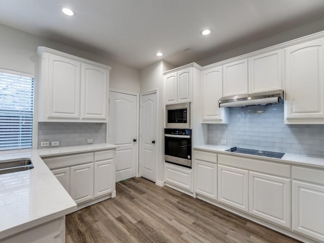 kitchen with white cabinets, light countertops, stainless steel oven, and under cabinet range hood