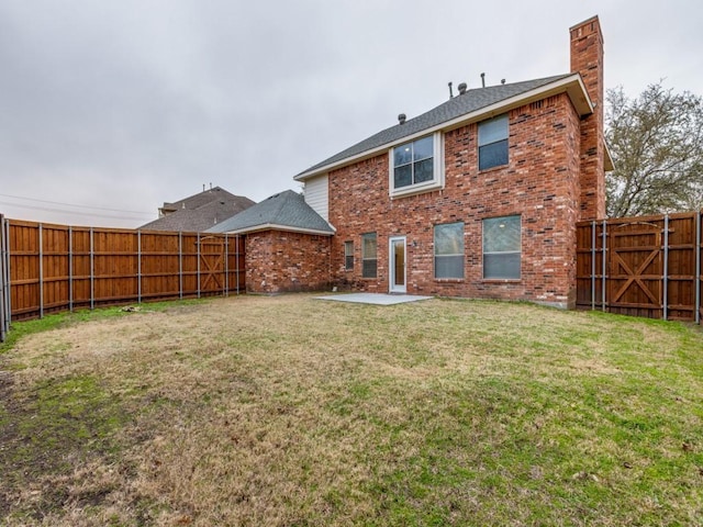 back of house with brick siding, a yard, a chimney, a patio area, and a fenced backyard