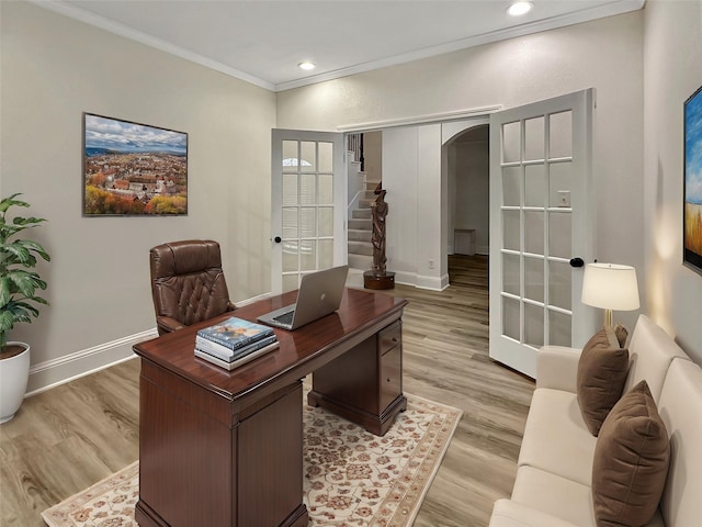 office space featuring arched walkways, baseboards, french doors, light wood finished floors, and crown molding