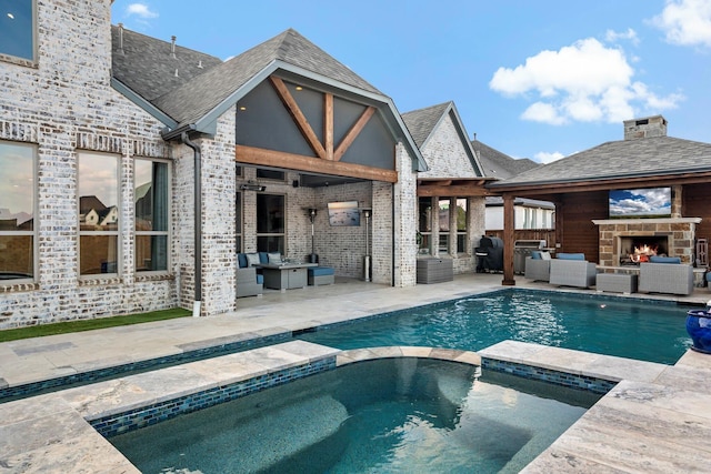 view of swimming pool with a pool with connected hot tub, a patio area, and an outdoor living space with a fireplace