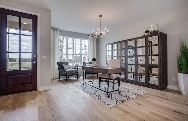 office area with baseboards, an inviting chandelier, and light wood-type flooring