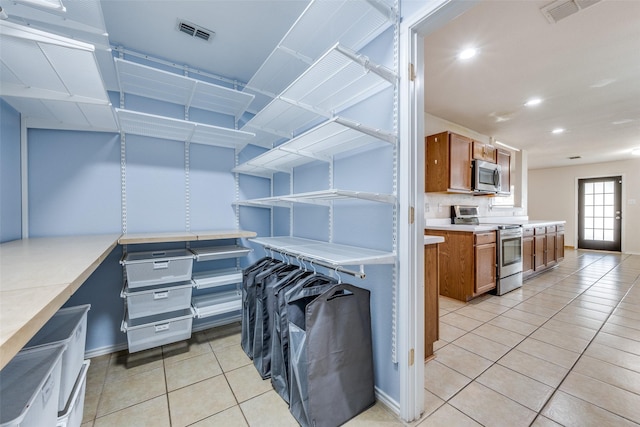 kitchen with visible vents, appliances with stainless steel finishes, brown cabinets, and light countertops