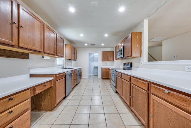 kitchen featuring light tile patterned floors, appliances with stainless steel finishes, light countertops, a sink, and brown cabinets