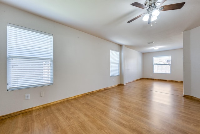 unfurnished room with baseboards, visible vents, a ceiling fan, and light wood finished floors