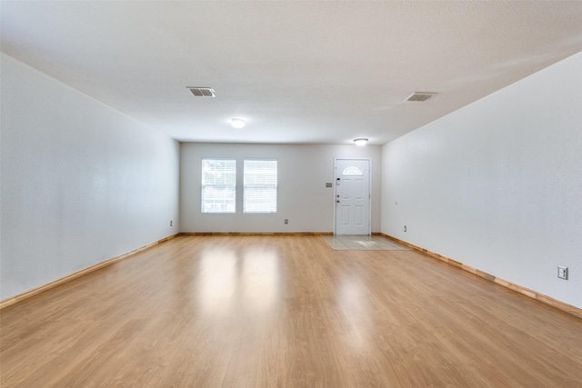 empty room featuring visible vents, light wood-style floors, and baseboards