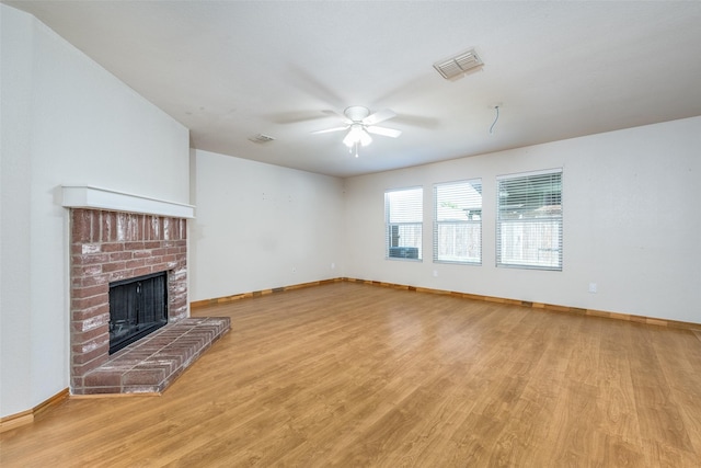 unfurnished living room with ceiling fan, a fireplace, visible vents, and light wood-style floors