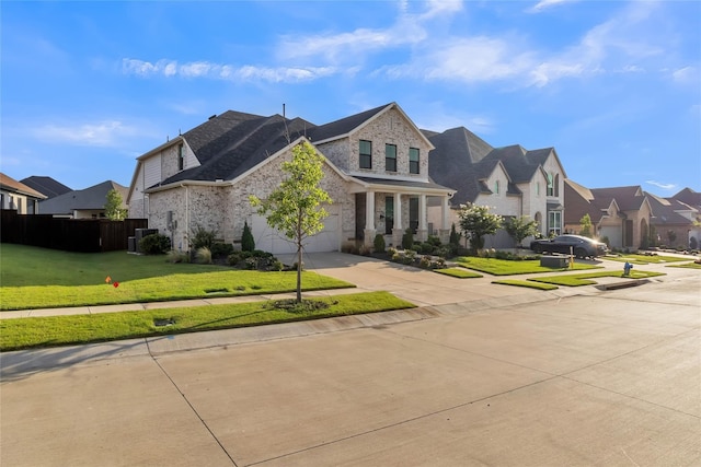 view of front of home with fence, driveway, stone siding, a residential view, and a front yard