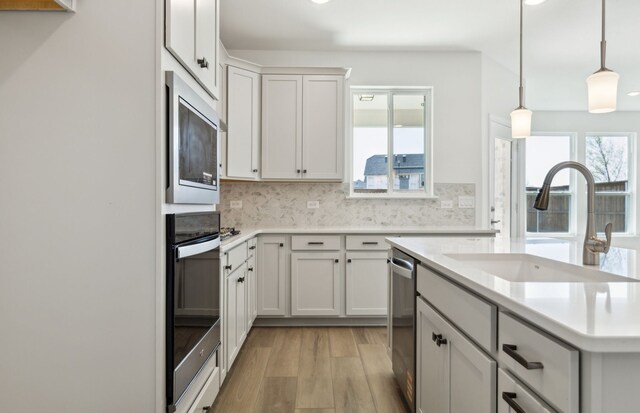 5917 Mayer Ave, Pilot Point, TX 75009 - kitchen featuring appliances with stainless steel finishes, a sink, light wood-type flooring, light countertops, and a kitchen island